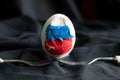 One white egg with the flag of Russia is broken stands on forks on a black background, Russia lost the war, Easter and