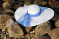 one white female hat with broad brim and blue ribbon on stones Bank rivers