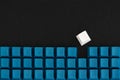 One white keycap among blue keyboard buttons on the black background. Be different concept. Royalty Free Stock Photo