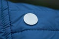 Metal button rivet on dark blue fabric