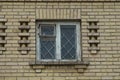 One white old wooden window with iron bars on the brown brick wall Royalty Free Stock Photo