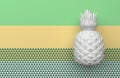 One white pineapple isolated on a background with a pale green, yellow and white stripe and triangles. Tropical exotic fruit with
