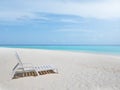 One white plastic beach chair on white sand beach with bright clear blue sky and colorful sea water. Royalty Free Stock Photo