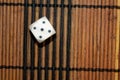 One white plastic dice on brown wooden board background. Six sides cube with black dots. Number 5 Royalty Free Stock Photo