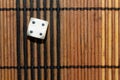 One white plastic dice on brown wooden board background. Six sides cube with black dots. Number 4 Royalty Free Stock Photo