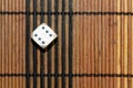One white plastic dice on brown wooden board background. Six sides cube with black dots. Number 6 Royalty Free Stock Photo