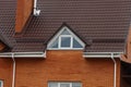 One white triangular window on a red brick wall of the attic of a private house