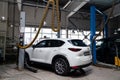 One white used car Mazda CX-5 on a lift for repairing the chassis and engine in a vehicle repair shop. Auto service industry