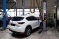 One white used car Mazda CX-5 on a lift for repairing the chassis and engine in a vehicle repair shop. Auto service industry