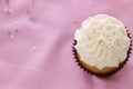 One white wedding cupcake on a pink tablecloth