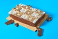 One whole checkered rectangular cake on bamboo mat near broken chocolate bar with nuts lies on blue table on party Royalty Free Stock Photo