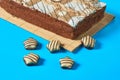 One whole checkered rectangular cake on bamboo mat near chocolate candy lies on blue table on party. Celebration concept Royalty Free Stock Photo