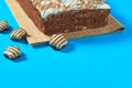 One whole checkered rectangular cake on bamboo mat near chocolate candy lies on blue table on party. Celebration concept Royalty Free Stock Photo