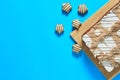 One whole checkered rectangular cake on bamboo mat near chocolate candy lies on blue table on party. Celebration concept Royalty Free Stock Photo