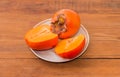 One whole and cut in half of persimmon on saucer Royalty Free Stock Photo