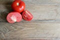 One whole and several cut tomatoes red, close-up isolated on brown wood backgroun Royalty Free Stock Photo