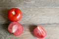 One whole and several cut tomatoes red, close-up isolated on brown wood backgroun Royalty Free Stock Photo