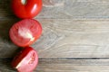 One whole and several cut tomatoes red, close-up isolated on brown wood backgroun Royalty Free Stock Photo