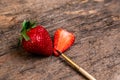 One whole strawberry and one half strawberry with paint brush on a dark wooden surface with space to write on the right Royalty Free Stock Photo