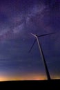 One wind turbine with beautiful milky way in background with bright stars over flat land at midnight
