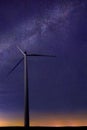 One wind turbine with beautiful milky way in background with bright stars over flat land at midnight