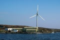 One wind turbine installed by the ocean. Clean blue sky and water surface. Alternative energy source in time of fuel and gas Royalty Free Stock Photo