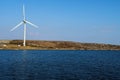 One wind turbine installed by the ocean. Clean blue sky and water surface. Alternative energy source in time of fuel and gas Royalty Free Stock Photo