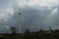 One wind turbine for renewable wind energy on horizon under the cloudy sky during the spring day on hills of Romania. Copy space Royalty Free Stock Photo