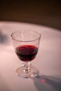 one wine glass with red wine standing on white table Royalty Free Stock Photo