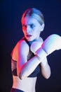 One Winsome Active Female Boxer Posing in White Gloves And Making Hit Against Dark Background With Colorul Lights