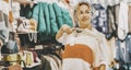 One woman doing shopping activity inside a garment clothes store smiling and looking sweaters. Sales holiday discount season on Royalty Free Stock Photo