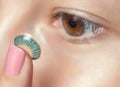 One woman holds a blue contact lens on her finger. Eye care and the choice between the means to improve vision Royalty Free Stock Photo