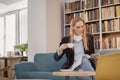 one woman, one person 40 years old, holding coffee cup, reading magazine, in library, book store, book shop, sitting in sofa. Royalty Free Stock Photo