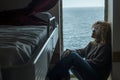 One woman passenger inside cabin boat cruise ferry having relax sitting near the window with ocean sea in background outside. Royalty Free Stock Photo