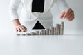 One woman putting coin on growth coins graph in white suit, step up growing business to success and saving for retirement concept