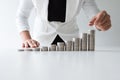 One woman putting coin on growth coins graph in white suit, step up growing business to success and saving for retirement concept