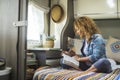 One woman reading a book sitting inside a modern camper van motorhome and enjoy relax indoor leisure activity alone. Independent Royalty Free Stock Photo