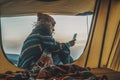 One woman sitting at the tent door enjoying freedom and exploration travel vacation using mobile phone and internet connection to