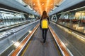 Woman traveller with backpack go on moving walkway travolator in new Hamad International Airport. Back view