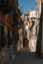 One woman is walking along the narrow and bright street of sunny Venice, Italy