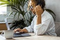 One woman worker alone using computer and headset to made video voice call at the desk in small business home office leisure Royalty Free Stock Photo