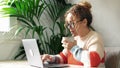 One woman working with laptop and blowing on warm herbal tea before drink. Serene worker online sart working people with coffee or