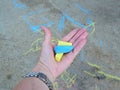 one womans hand holds crayons, drawing with chalk on the asphalt by young children. close-up, selective focus