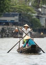 One women rower stands on her simple rowboat.