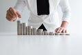 One woman putting coin on growth coins graph in white suit, step up growing business to success and saving for retirement concept