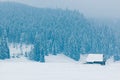 One wooden house stands on a snowy valley, in the background of snow covered mountains and fir trees Royalty Free Stock Photo