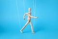 One wooden puppet with strings on light blue background