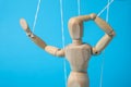 One wooden puppet with strings on light blue background