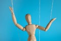 One wooden puppet with strings on light blue background