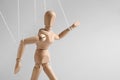 One wooden puppet with strings on light grey background. Space for text